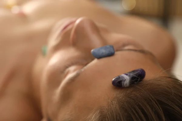 Relaxed Man Receiving Crystal Healing Therapy With Stones On Face